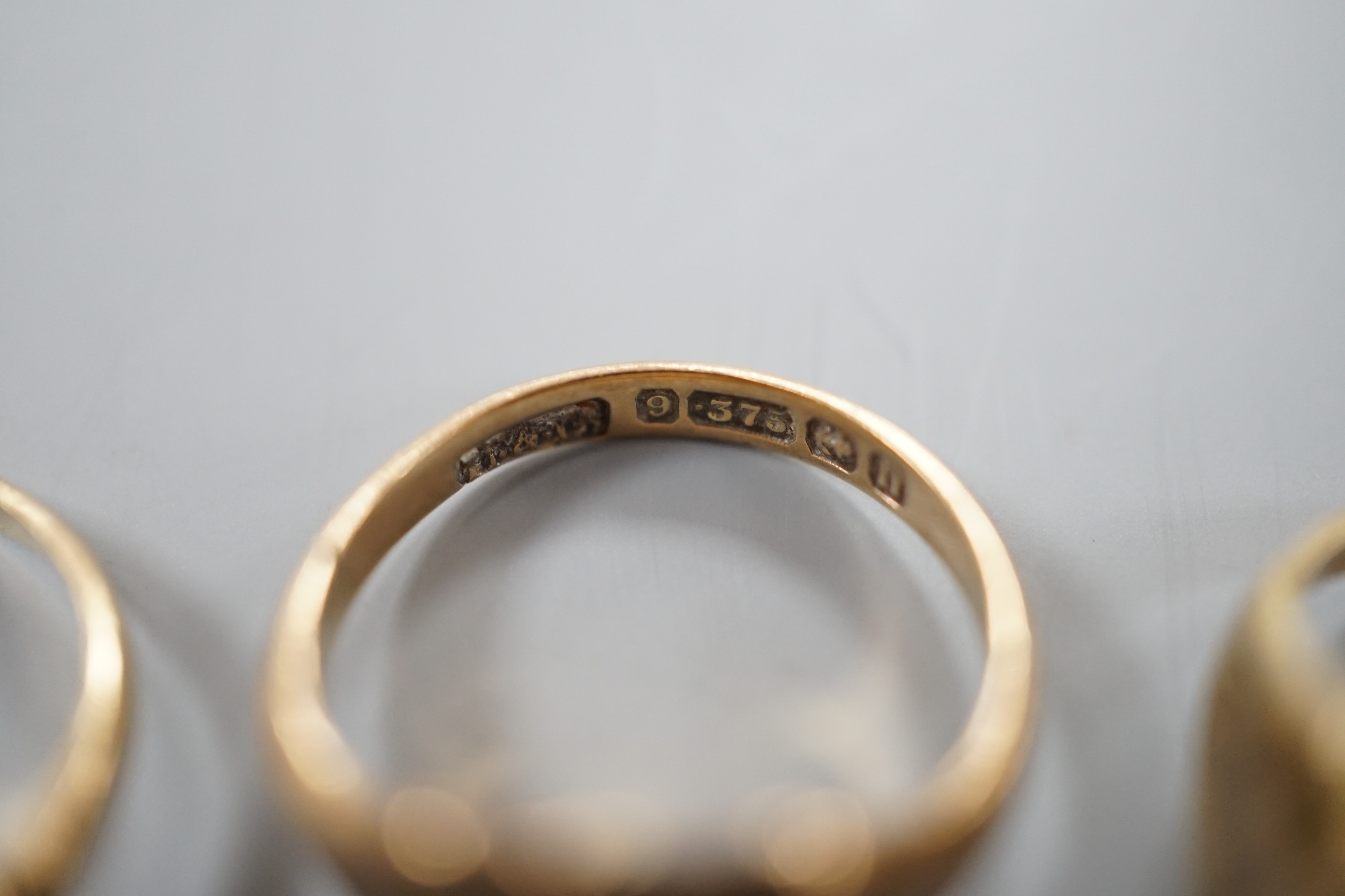 A 19th century yellow metal mourning ring, with plaited hair beneath a glazed panel size L, together with two later 9ct gold signet rings, gross weight 6.3 grams.